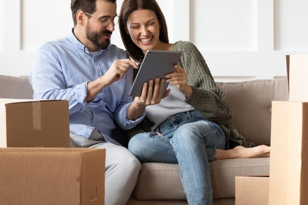 Couple On The Sofa In Thier New Home With Ipad Mobile