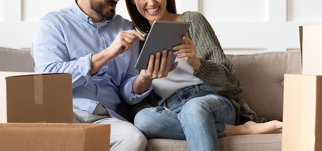 Couple On The Sofa In Thier New Home With Ipad Mobile